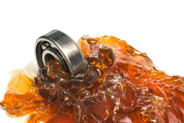 Closed up macro, ball bearing put into yellow transparent lithium grease isolated on white...