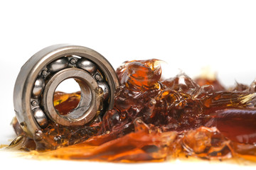 Closed up macro, ball bearing put into yellow transparent lithium grease isolated on white background with copy space, engineering and industrial concept