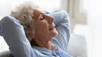 Close up peaceful older woman relaxing on cozy sofa