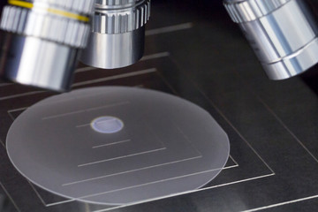 Close up of examining a sample of sapphire wafer under the microscope in laboratory.A semiconductor...