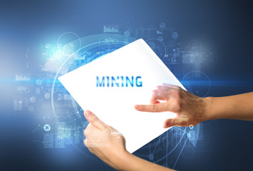 Hand holdig futuristic tablet with MINING inscription, new technology concept