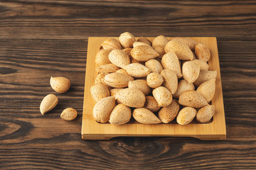 inshell almonds on a wooden stand, close-up, copy space