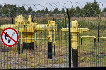yellow gas holder behind the fence with a sign smoking is prohibited. summer