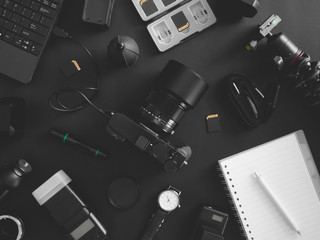 top view of work space photographer with digital camera, flash, cleaning kit, memory card, tripod and camera accessory on black table background