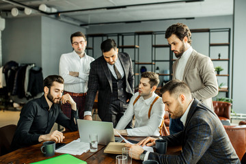 friendly and successful business crew coworking in office, gathered to discuss and share opinions about business strategy, cooperation of young leaders, business partners in tuxedo