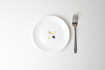 Multivitamin and mineral supplements. Plate with tablets. Fork aside. Meal replacement.