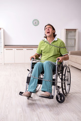 Young male invalid in wheel-chair suffering at home