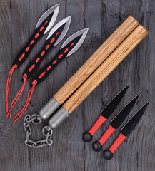 nunchucks and throwing knives on wooden background