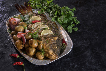 Large baked carp with herbs, lemon and potatoes. Traditional Polish or Jewish cuisine. The view from the top. Free space for text. Copy space