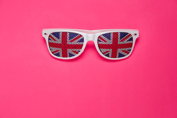 White rimmed sunglasses with UK flag on pink isolated background. Free space for your text.