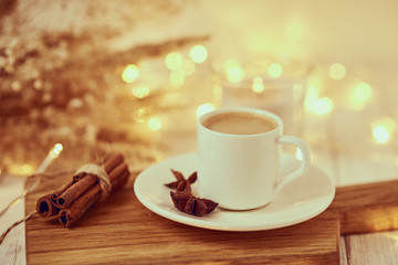 Cup of coffee with a garland lights and decoration on table. Cozy home concept