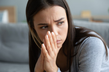 Close up unhappy young woman thinking about problems alone