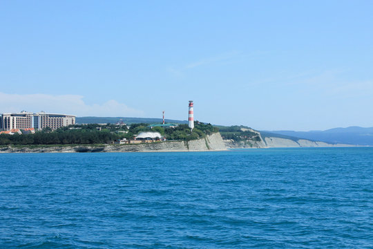Coastal lighthouse on the edge of a rocky promontory in the black sea, the city of Gelendzhik. Located to the left of the frame. Landscape. Horizontal photo. Blurred background. Summer. opy space