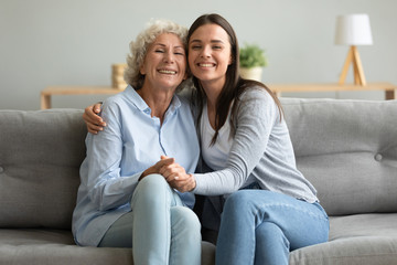 Portrait happy grandmother and granddaughter hugging, sitting on couch