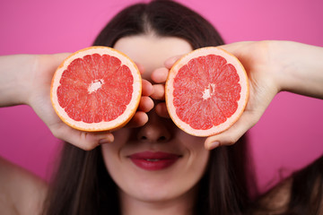 Healthy food, vitamin C, body care, cosmetology. Happy cheerful funny girl holding halves of grapefruit near face