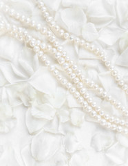 Obraz na płótnie Canvas Pearl necklace on a background of white rose petals. Ideal for greeting cards for wedding, birthday, Valentine's Day, Mother's Day