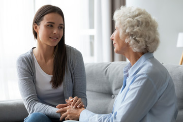 Young woman talking with grandmother, holding hands, supporting