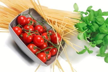 dynamic perspective of a bowl with cherry tomatoes with pasta and basil plant with white background