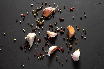 cloves of garlic and a mixture of peppers on a dark background