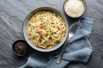 Classic pasta Carbonara, hearty Italian dish made with Spaghetti, egg, fried bacon, topped with grated Parmesan cheese and black pepper