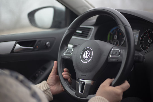 Moldova, Chisinau - 01.17.2020: CLose-up of female hands driving Jetta Hybrid.