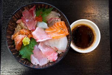 Premium fresh raw seafood mixed rice bowl (Kaisen-don/ Japanese tasty food), Japanese Rice with sashimi of tuna, Maguro, Otoro, salmon, squid and ikura (Salmon eggs) on wood background - obrazy, fototapety, plakaty
