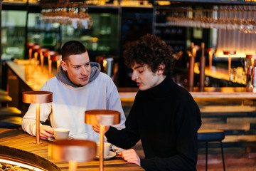 Two young guys friends with beards arguing in a coffee shop