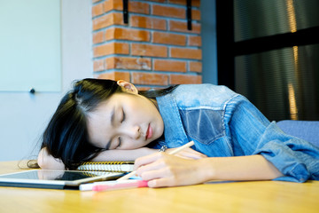 Young asian woman sleeping as exhausted from working with papers at her office desk, Asia student...