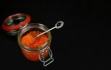 Red caviar in a jar in a black background