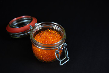 Red caviar in a jar in a black background