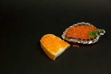 Red caviar spreading bread on a black background