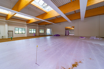 Inside a large factory building, purple insulation panels are laid on the floor