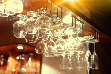Empty  glasses hanging above the bar in the restaurant. - obrazy, fototapety, plakaty