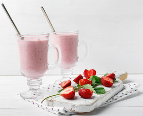 Glass of fresh strawberry and yogurt smoothie on white wooden table
