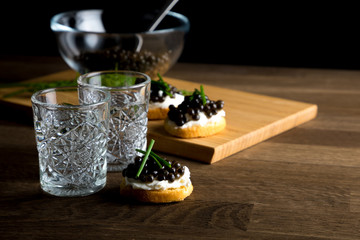 Black Caviar, shots of russian vodka on wooden table, copy space