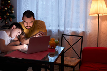 young caucasian man help his son to study, to do homework at home, using modern laptop and exercise...