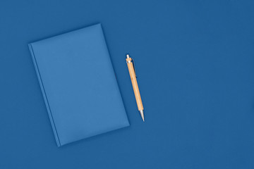 Notebook and pen on blue background. Business concept. Top view, flat lay, copy space. Trendy color of the year 2020.