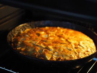 Homemade baking. Round apple pie in a black pan in the oven.