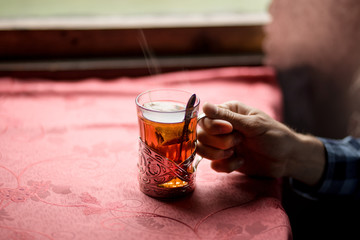 man hand hold hot black tea in glass holder.