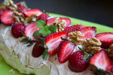 Meringue cake with mint strawberries and walnuts on a plate