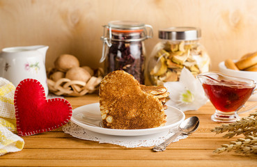 Fritters, pancakes in the form of hearts with jam on a light wooden background with a red heart, romantic breakfast for Valentine's Day. Mothers Day.