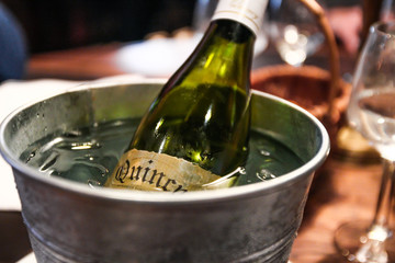 White Wine glass bottle in a bucket full of ice and water to keep it fresh. Restaurant in Honfleur, Normandy, France.