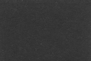 Cardboard black abstract texture close-up. Dark old paper background. Grunge concrete wall. Vintage blank wallpaper.