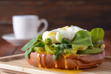 Poached egg with green cucumber, arugula beet leaves , smoked salmon and spices on a toast, wooden background. Healthy French breakfast concept 