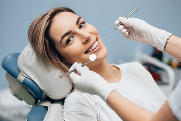 portrait of young smiling blond good-looking woman on dental examination, treating teeth in professional orthodontic clinic