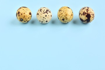 Speckled quail eggs for Easter holiday on neutral light blue background. Raw organic quail egg. Easter eggs. Ingredients for healthy protein breakfast. Keto diet. Easter background traditional symbol 