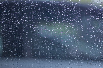 Naklejka na ściany i meble Blurred, raindrops, perched on a glass after a rain background image