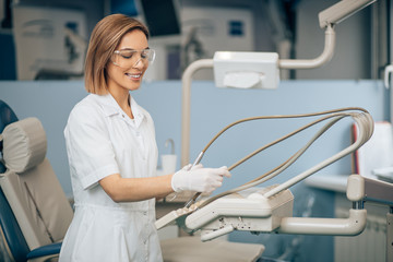 portrait of positive smiling dentist woman in white uniform looking at camera, careful doctor in...