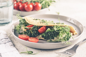 Vegan chickpea omelet with broccoli, tomatoes and seedlings. Healthy vegan food concept.
