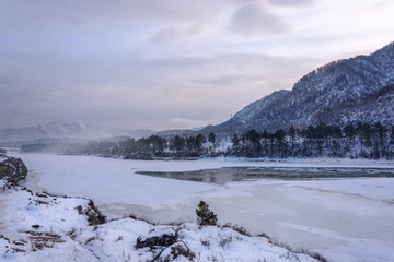 Landscape with snow-capped mountains and a freezing mountain river